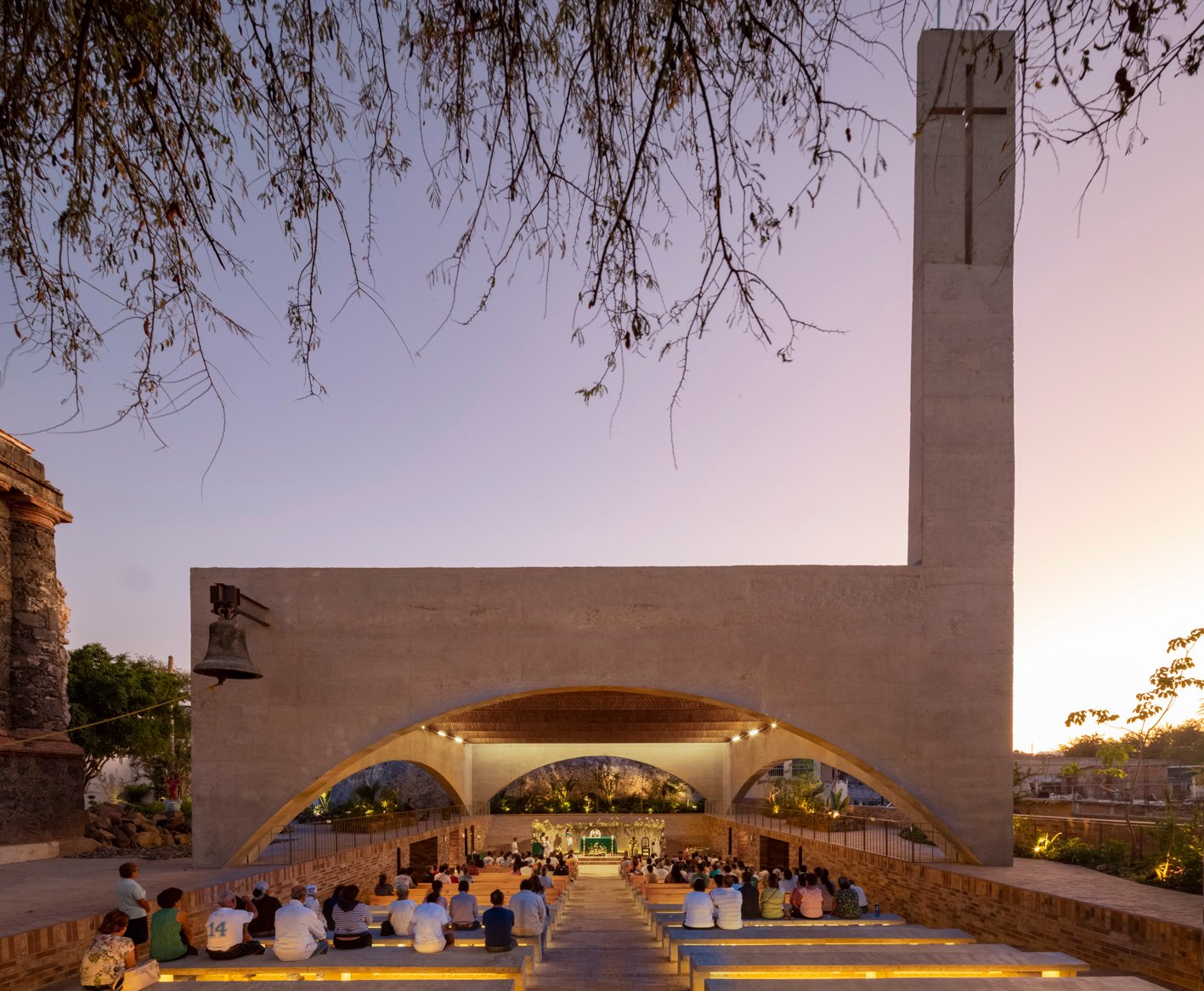Santuario de Nuestro Señor de Tula al atardecer, con fieles sentados frente al altar y una torre con cruz.
