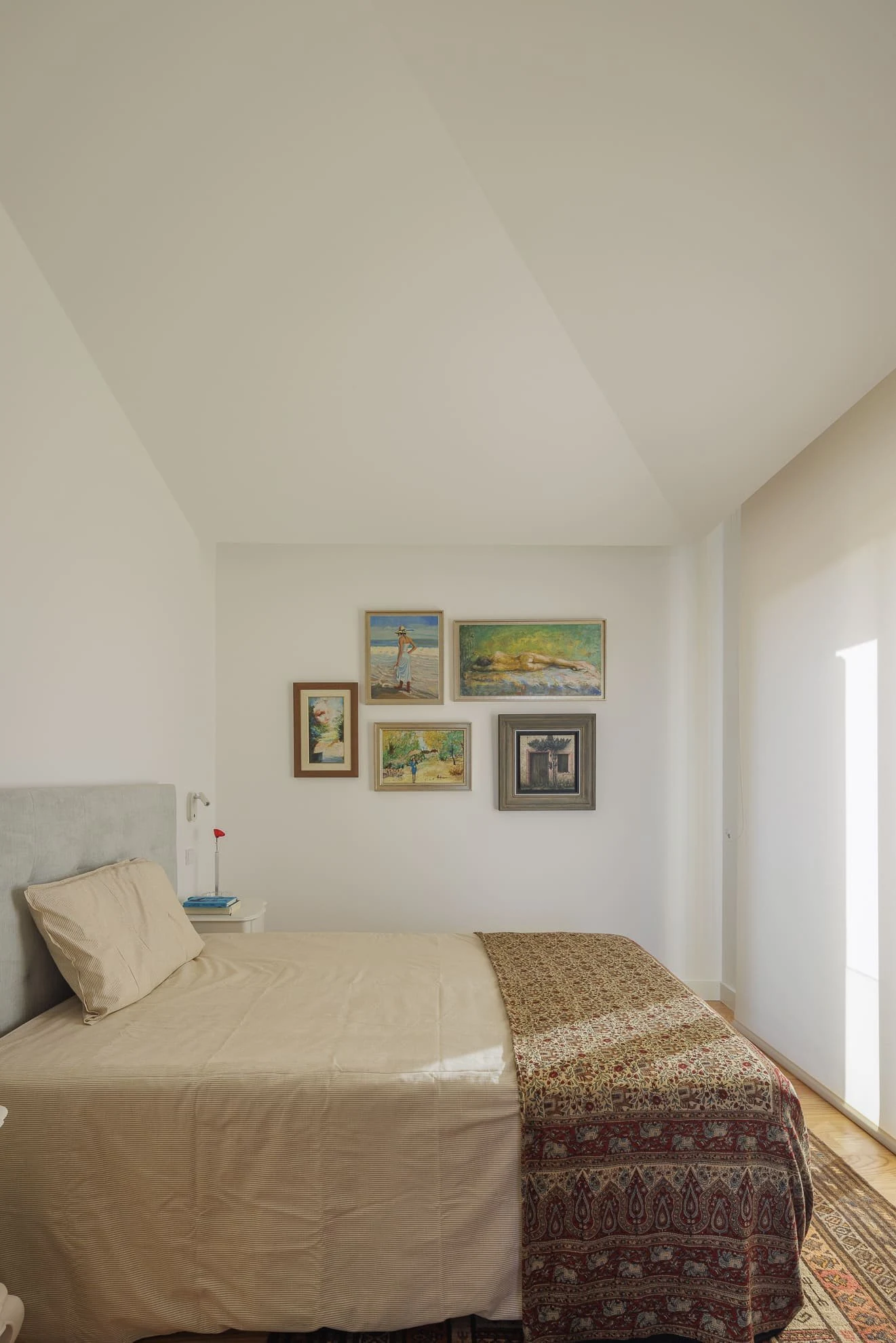 Dormitorio bajo la cubierta inclinada de Casa CC, de Esquissos