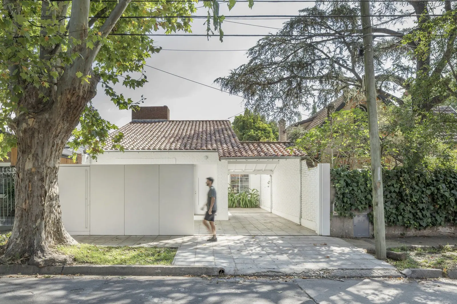 Fachada principal con muro blanco y cubierta de teja de Casa Florida, de Di Marco + Robles Arquitectos