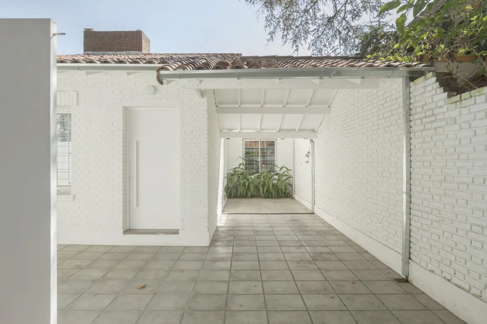 Porche de acceso con muros de ladrillo pintado de Casa Florida, de Di Marco + Robles Arquitectos