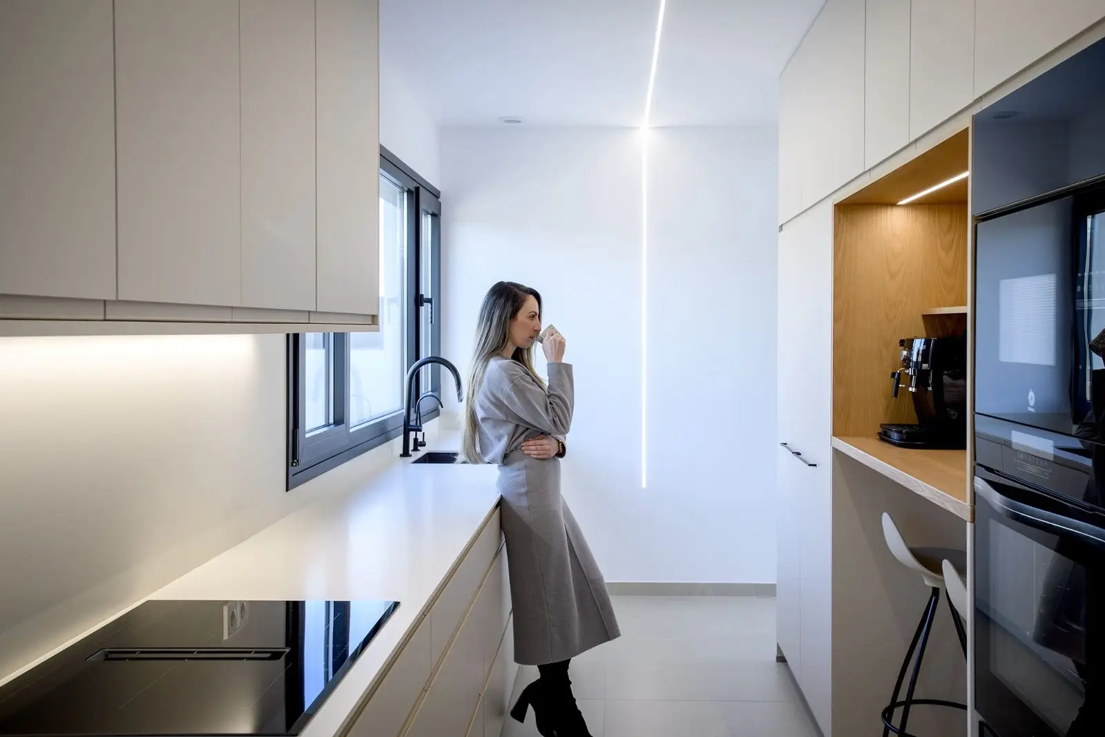 Cocina con mobiliario blanco y espacio de desayuno de Casa Olivera, de Miragall Romaguera i arquitectes associats