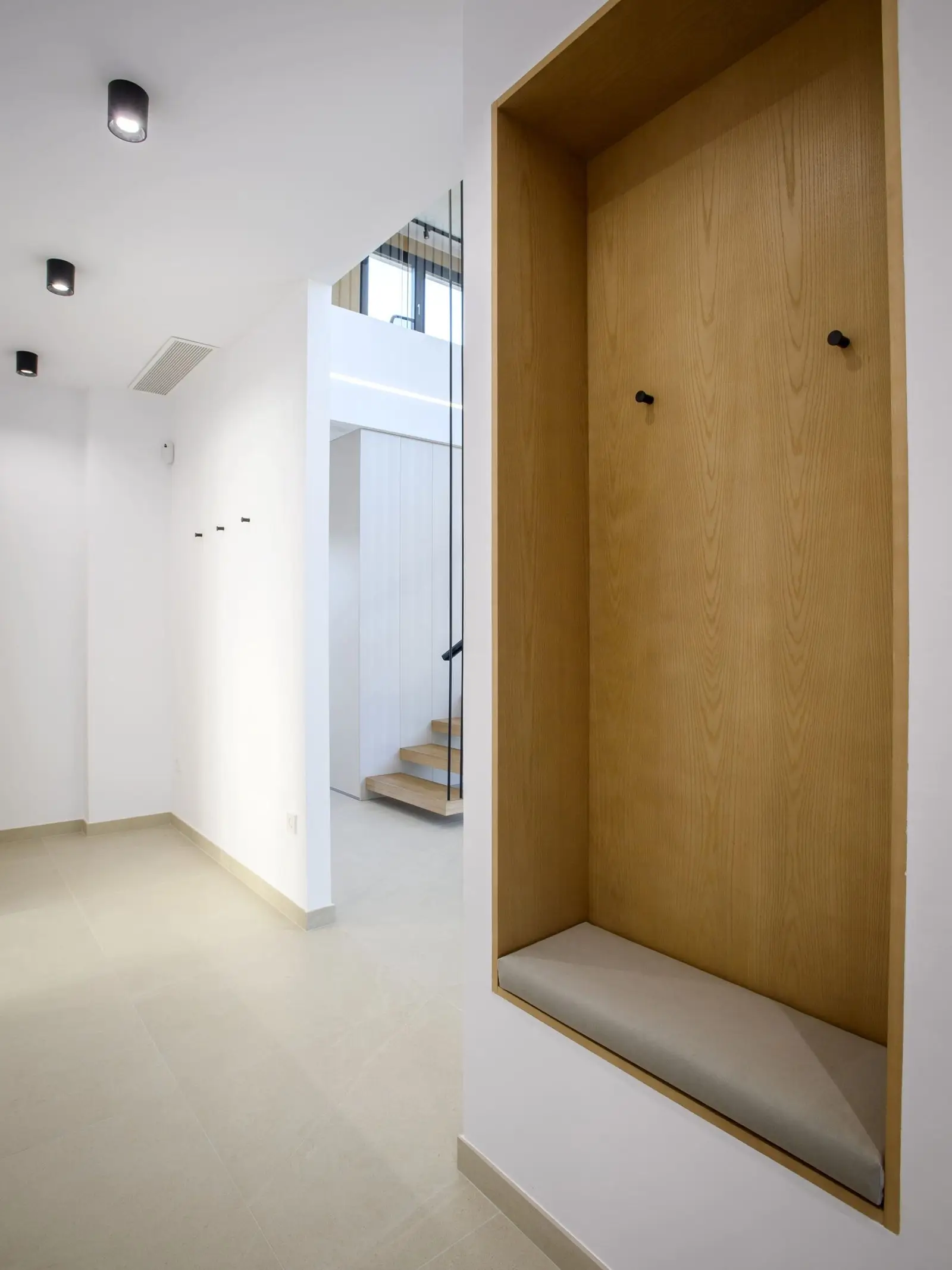 Recibidor con banco y revestimiento de madera de Casa Olivera, de Miragall Romaguera i arquitectes associats