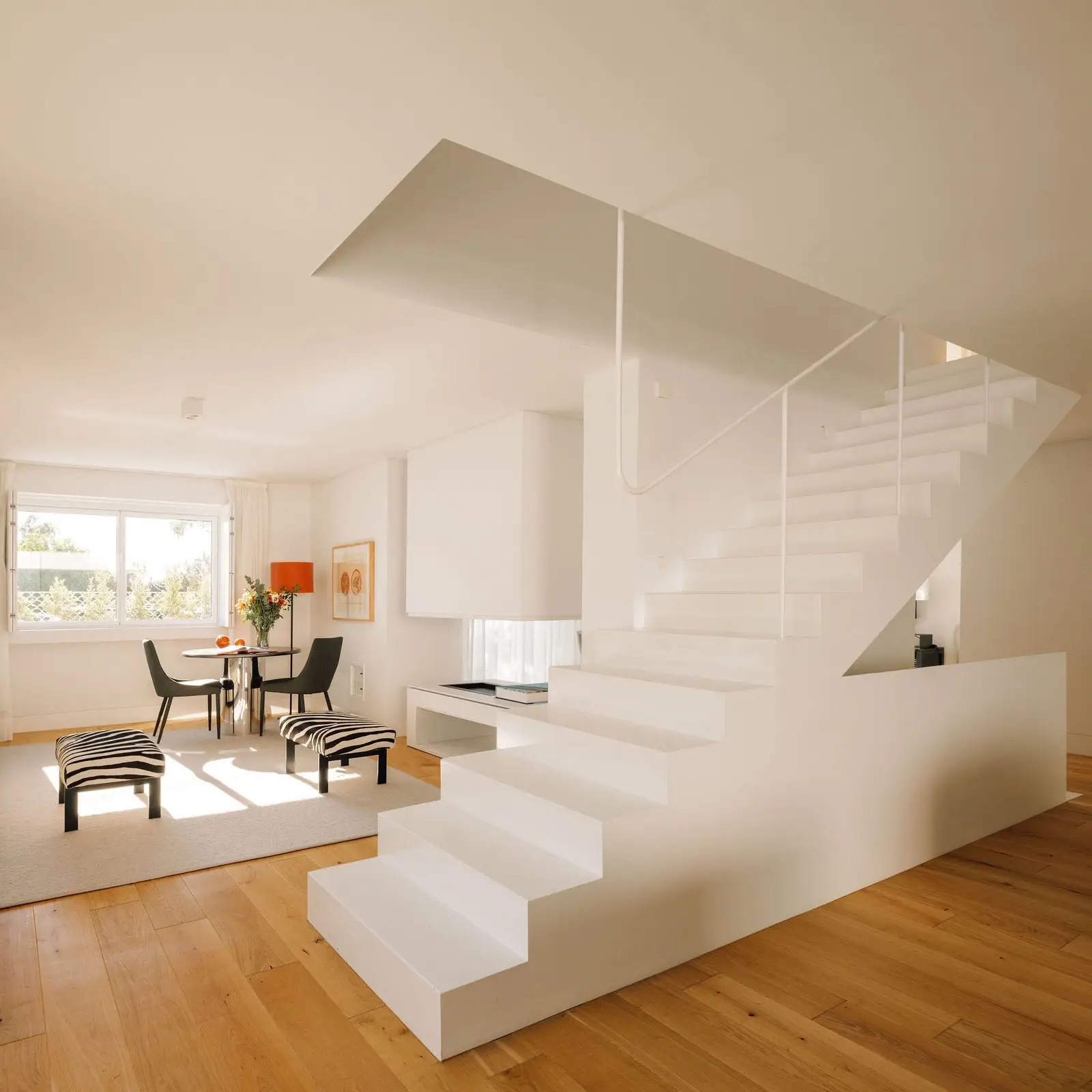 Escalera central y comedor de la vivienda con suelo de madera
