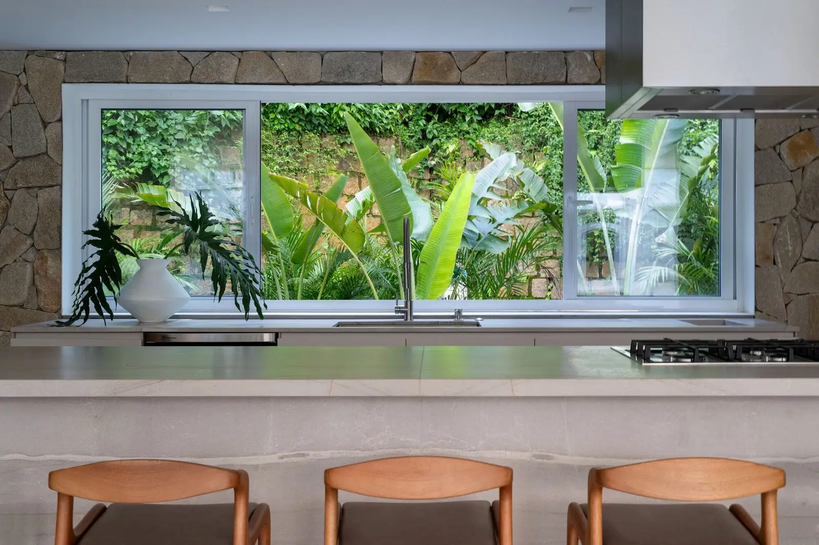 Barra de cocina de Pabell&oacute;n Zona Sur ante una ventana al jard&iacute;n