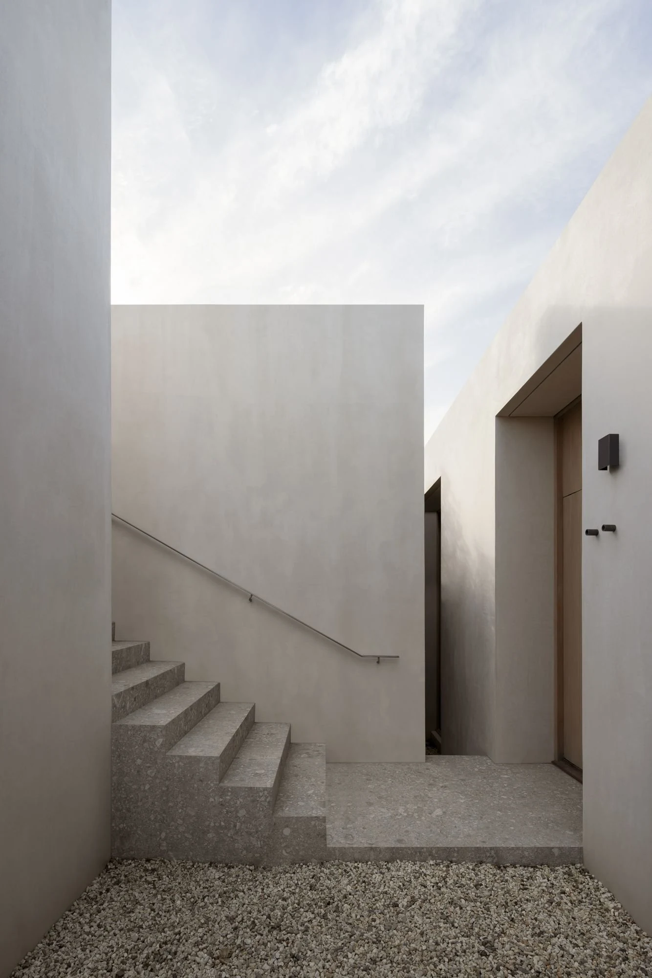 Escalera de acceso entre muros blancos de Residencia EPSC, de Davidov Architects
