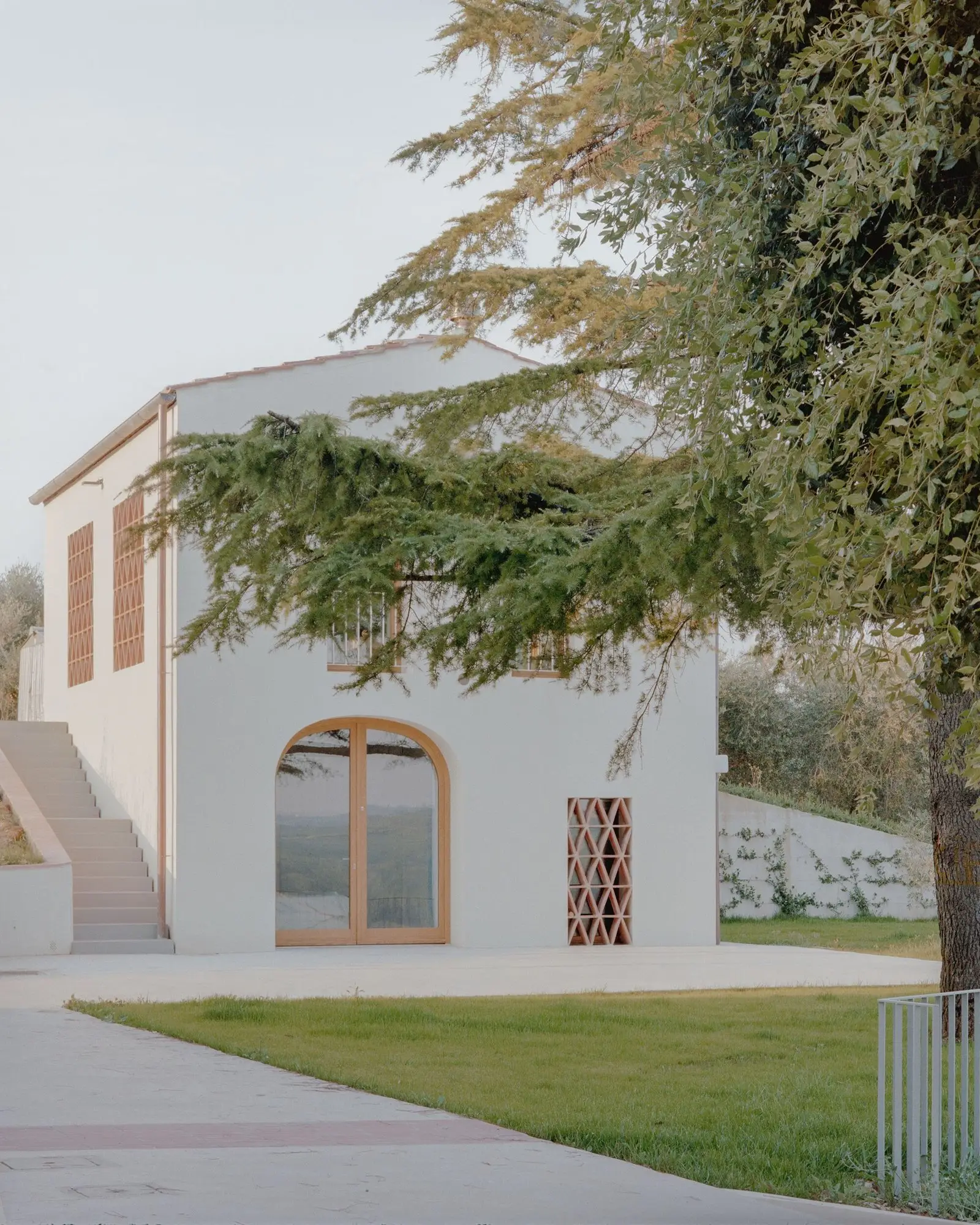 Vista exterior del granero restaurado con su acceso en arco y jard&iacute;n