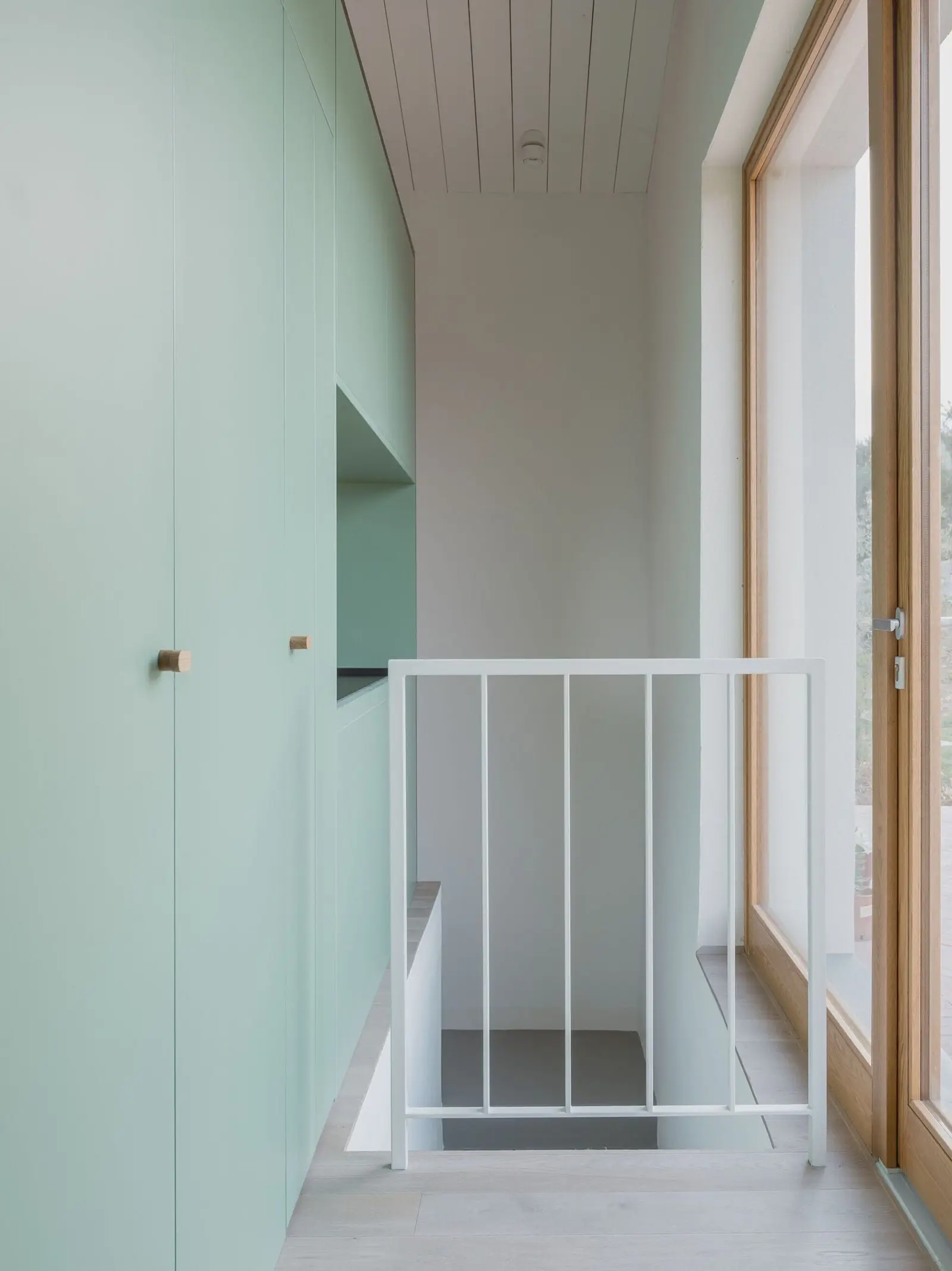 Escalera interior junto al volumen verde y la carpinter&iacute;a de madera