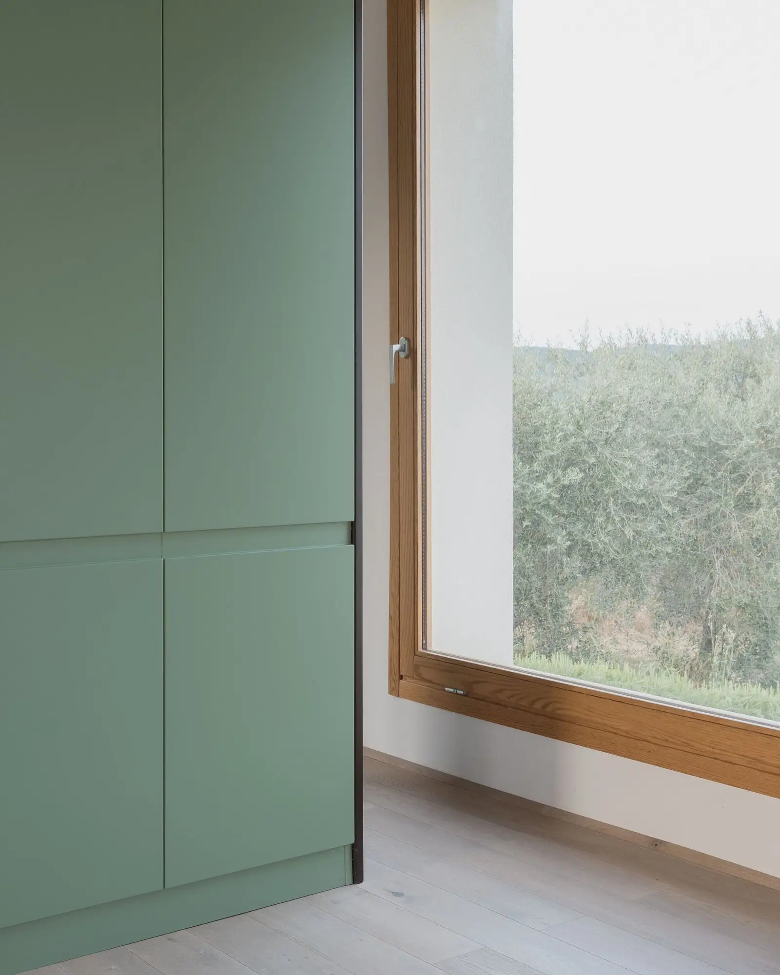 Ventana de madera junto al mueble verde con vistas al paisaje
