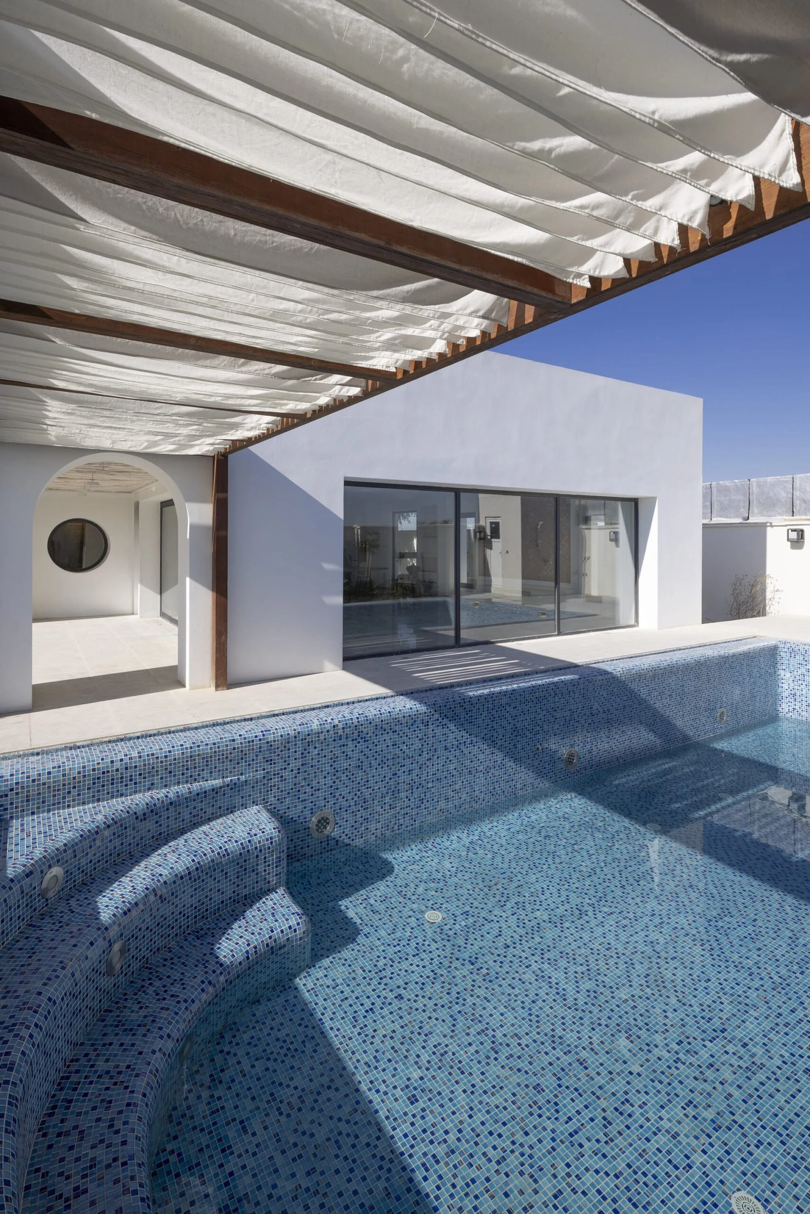 Piscina revestida con azulejos turquesa junto al sal&oacute;n de Villa 144, de Lin3rd Architects
